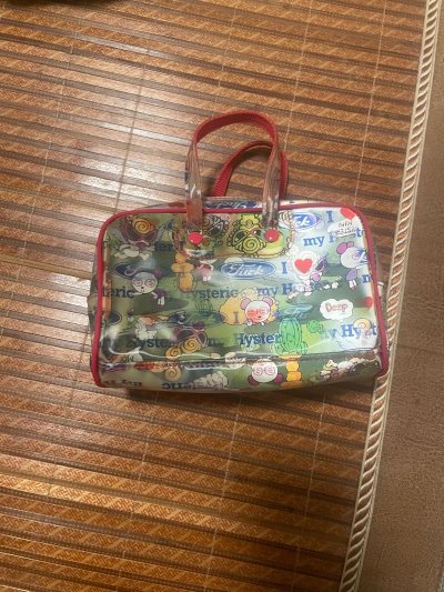 海淘到这个Hysteric Glamour风格的手提包太绝了！满印的趣味图案和标志性文字，红边点缀超有辨识度，PVC材质复古又特别。小小一只很能装，日常当化妆包或手拎包都很吸睛。这种小众潮牌设计在国内很难遇到，海淘等了好久但收到就被它的个性戳中，搭配甜酷风穿搭绝绝子...