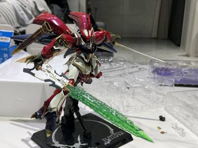 mb系列中的维尔宾，他将生物曲线与冷硬装甲完美融合。铠甲红色珍珠漆随光线流转渐变光泽。动态关节设计突破传统机甲框架，腿部多层复合结构在运动中舒展如猎豹，脚踝联动装置随动作改变轮廓线条；“圣剑步枪”通过电镀工艺实现射击与斩击形态切换。整体发扬了圣战士的幻想基因，彰显了...