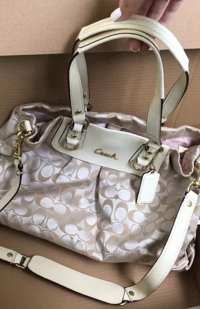 蹲了好久终于抢到这只COACH绸缎托特包！拿到手的质感比图片还要惊艳——浅香槟色的缎面布料带着细腻的光泽感，灯光下会泛着温柔的柔光，经典的C形压纹铺满包身，低调又透着大牌的精致感。包型是软乎乎的褶皱设计，不会像硬挺款那样显得笨重，日常不管是手提还是斜挎（自带可调节长...