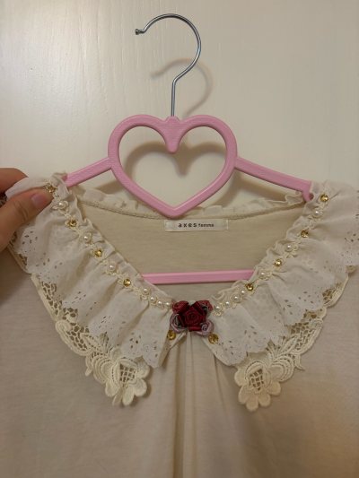 这款axes femme上衣的蕾丝领太戳甜系审美！镂空花边叠珍珠、金饰，暗红玫瑰点缀得温柔又精致，浅米色基底衬得质感柔和，是把浪漫细节焊在领口的少女感单品~