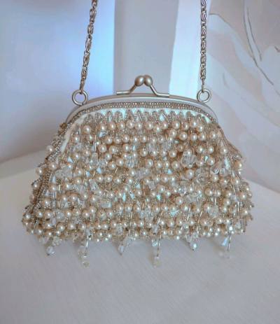 这只珍珠串珠包，360度全部手工缝制了细密珍珠和剔透水晶串珠，珠子是灌银珠，很精致很有质感
包底也是细细密密的流苏珍珠串珠，很少见
在水晶流苏吊坠的点缀下，华丽的不能再华丽了
口金也是超有质感的金属磨砂材质
和包包颜色一致的银色，非常高级