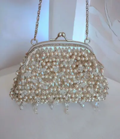 这只珍珠串珠包，360度全部手工缝制了细密珍珠和剔透水晶串珠，珠子是灌银珠，很精致很有质感
包底也是细细密密的流苏珍珠串珠，很少见
在水晶流苏吊坠的点缀下，华丽的不能再华丽了
口金也是超有质感的金属磨砂材质
和包包颜色一致的银色，非常高级