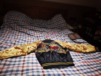 这件金色与黑色交织的龙纹横须贺夹克，无疑是我近期最得意的收藏。开箱瞬间就被震撼——黑色缎面深邃如夜，其上以金线精密刺绣的蟠龙气势非凡，鳞片在光线下流转着细腻光泽。刺绣的立体感与缎面的柔滑形成绝妙对比，袖臂的日式纹样更添韵味。版型挺括利落，上身出乎意料地舒适。
它绝不...