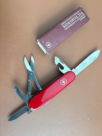 维氏91mm老款攀登者，三层工具带剪刀，酒红色老款盒子（一端舌盖掉了），主刀根部大V四行弩标根刻，一字轴剪刀，深槽红酒钻，距今三四十年的历史。
贴片反光新，工具未使用，很难得的收藏品相，老款做工更好，用料更足，耐用实用