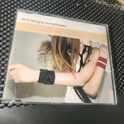蹲到艾薇儿《Complicated》的单曲CD太惊喜！封面里红白条腕带+黑纱手链的造型，完全是当年朋克少女的标志性穿搭。盘面的黑白磨砂设计质感满分，还带了《Complicated》的MV，翻开封套看制作信息，连编曲细节都写得超全，老粉拿到手直接梦回青春，实体碟的收藏...