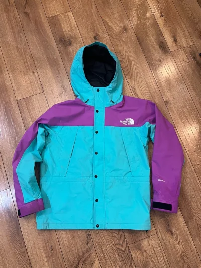 把90年代的山野色彩穿在身上！这件The North Face NP62236冲锋衣，青蓝与紫的撞色自带复古滤镜，Gore-Tex硬核防水，既能扛住户外风雨，也能成为城市街头的吸睛利器。