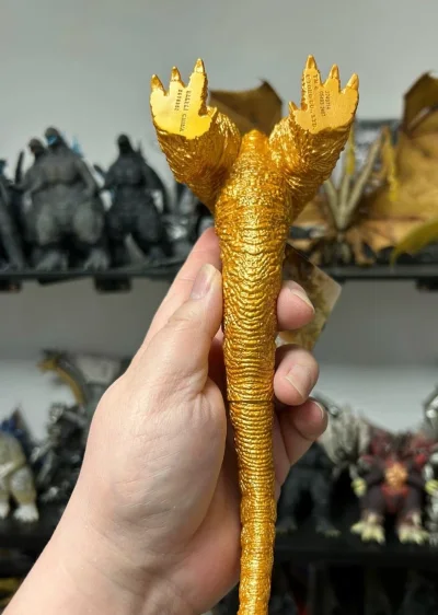 通体鎏金的哥斯拉-1.0手办，棘刺如锋锐金刃，鳞纹在光下泛着金属光泽，将怪兽的威严与压迫感尽数凝于掌心。