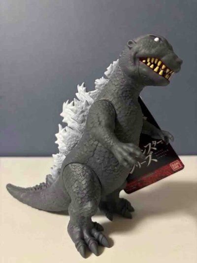 这是1954版哥斯拉雏形款软胶，还原了初代经典造型，灰黑躯体搭配白色背棘，皮肤纹理与利齿细节刻画到位，复古感与纪念意义兼具，是系列原点的代表性周边。