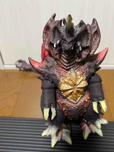 这款戴斯特洛伊亚软胶，以黑红为主色调，背部鲜红翼状结构与渐变尾脊极具张力。头部尖角与狰狞利齿还原度拉满，胸口金色纹路与全身粗糙鳞片纹理刻画细腻，压迫感十足，是怪兽收藏中的经典反派款。