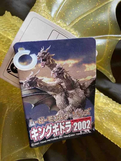 这是2002年王者基多拉的透明黄金限定版软胶。通体晶莹剔透的琥珀色带有细腻金闪点缀，质感奢华高级。三头龙形威严霸气，翅膀展开幅度大，鳞片纹理刻画精致，附带原装卡片，是极具收藏价值的限定老物。