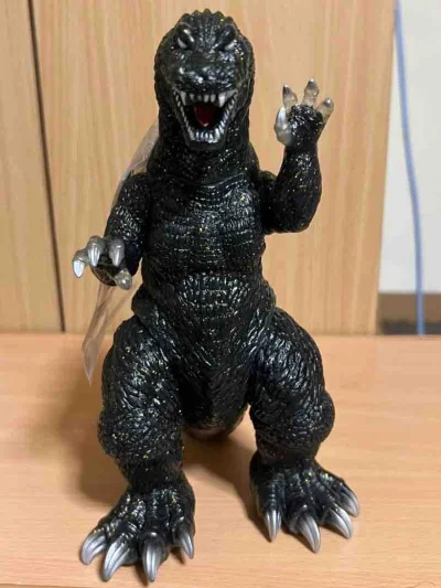 这款哥斯拉软胶通体黑底金闪质感，背鳍黄绿渐变层次分明，全身鳞片纹理粗犷立体，透明爪甲与利齿细节还原到位，附带原装标签，是经典耐看的收藏款。