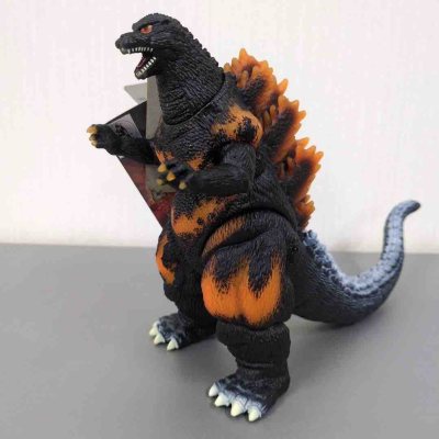 这款1995版红莲哥斯拉软胶，以黑底橙焰涂装还原核爆暴走状态，背鳍橙红渐变、腹部熔岩纹路极具视觉冲击力，尾部蓝灰纹理层次分明，姿态张力拉满，是承载终焉情怀的经典收藏款。