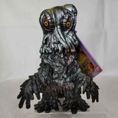 这款黑多拉（Hedorah）软胶通体暗金属质感，泥浆状褶皱纹理还原污泥怪兽特质，红黄眼瞳与滴落状肢体细节生动，充满怪诞诡谲的视觉张力，是极具辨识度的经典反派收藏款。