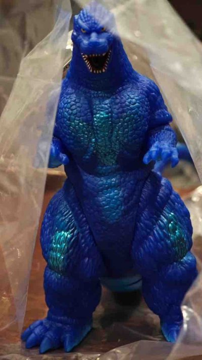 这款1991版哥斯拉限定蓝绿配色软胶，通体宝蓝质感，背鳍与胸腿处的青绿渐变点缀亮眼，鳞片纹理细密立体，姿态威严，是色彩极具辨识度的复古收藏款。