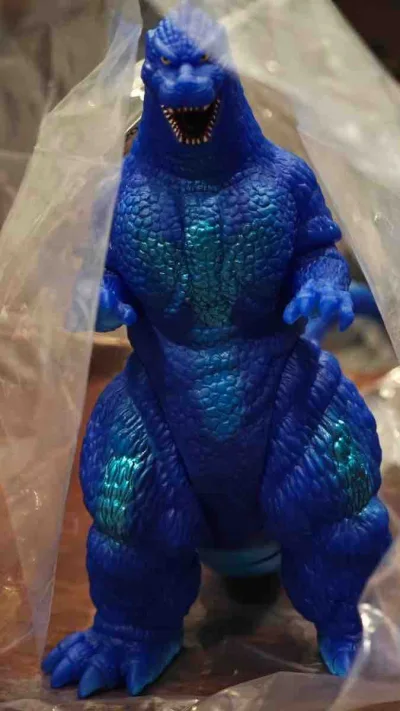 这款1991版哥斯拉限定蓝绿配色软胶，通体宝蓝质感，背鳍与胸腿处的青绿渐变点缀亮眼，鳞片纹理细密立体，姿态威严，是色彩极具辨识度的复古收藏款。