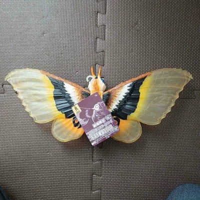 这款摩斯拉软胶翼展宽大，半透翼面纹理细腻，黄黑橙三色渐变层次丰富，眼状斑纹醒目生动，躯体绒毛质感与复眼细节刻画精致，尽显守护女神的华贵与灵动，是极具视觉美感的收藏款。