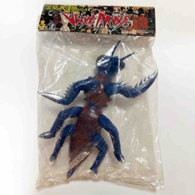 这只怪兽手办色彩冲击力拉满，宝蓝闪粉质感的肢体搭配红棕躯干，头顶莓果状凸起和长角造型怪异又醒目，镰刀状前爪细节锋利，复古软胶的粗犷感十足，是特摄怪兽里极具辨识度的虫型设计。