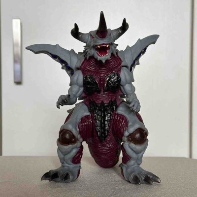 这只怪兽手办设计感拉满，灰红撞色对比强烈，背部棘甲与翼状结构层次分明，单角+双牛角的头部造型凶悍，翅膀上的蓝宝点缀和肌肉纹理细节都刻画得很细腻，整体充满力量感与压迫感，是极具视觉冲击力的特摄怪兽款。