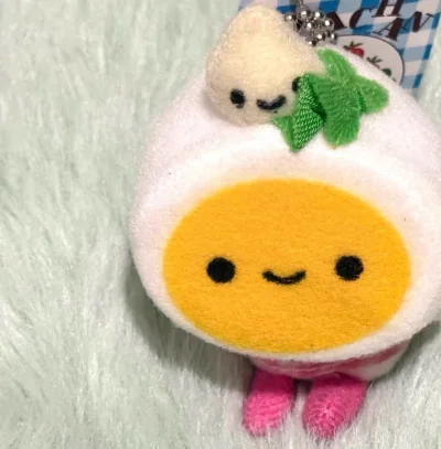 这次入手的荷包蛋Egg毛绒挂件太治愈了！粉白配色的荷包蛋造型软萌可爱，搭配粉格纹小围裙和头顶的小萝卜装饰，细节满满。毛绒质感柔软亲肤，挂在包上超吸睛，作为可爱风周边颜值与手感都在线，购物体验超满意！