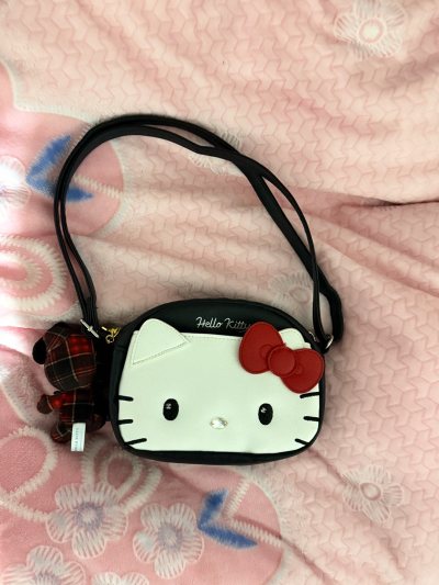 真的被这款Hello Kitty斜挎包狠狠拿捏了！经典的黑白红配色软萌又百搭，包身立体的凯蒂猫造型还原度超高，红色蝴蝶结精致又可爱，颜值直接拉满。皮质手感细腻顺滑，做工走线工整，没有多余线头，内里空间也很够用，日常装手机、口红、钥匙、纸巾完全没问题，背带长度可调节，...真的被这款Hello Kitty斜挎包狠狠拿捏了！经典的黑白红配色软萌又百搭，包身立体的凯蒂猫造型还原度超高，红色蝴蝶结精致又可爱，颜值直接拉满。皮质手感细腻顺滑，做工走线工整，没有多余线头，内里空间也很够用，日常装手机、口红、钥匙、纸巾