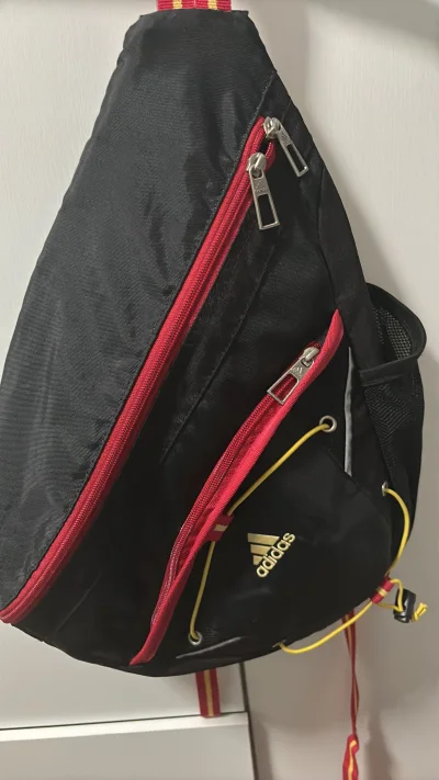 非常好看的一款弓箭包，超赞！黑红撞色搭配金色品牌标，再加上亮眼的黄色抽绳，复古运动感直接拉满！不对称的三角造型辨识度超高，不管是搭运动健身装，还是配休闲卫衣、工装风穿搭都超合适，妥妥的穿搭加分项，拍照巨出片，走在路上回头率超高！
