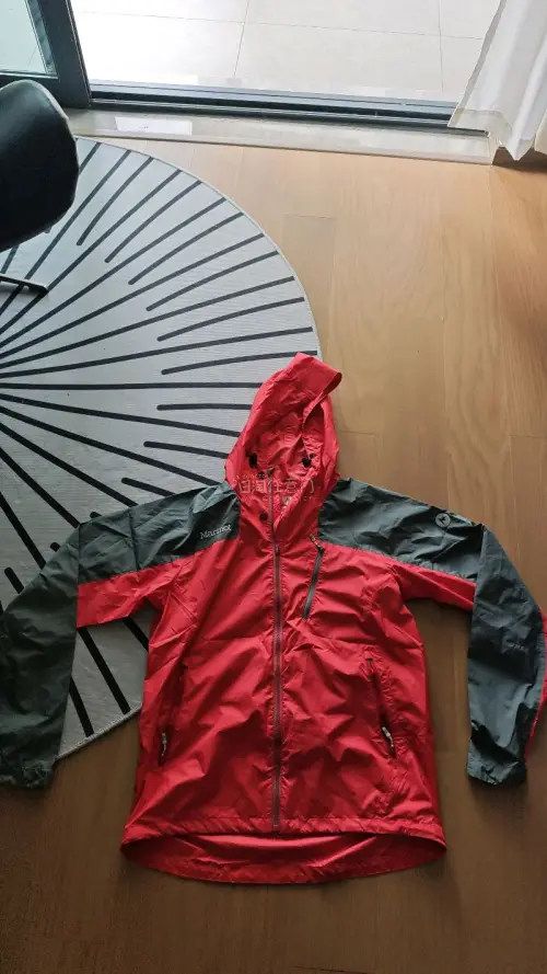 心心念念的Marmot冲锋衣了。经典的红黑撞色拼接设计，视觉上非常亮眼且具有活力，户外穿着辨识度极高，平时搭配休闲裤也很帅气。衣服拿在手里质感很棒，面料轻薄但挺括，摸起来顺滑，应该是具备专业防水透气性能的科技面料。细节方面无可挑剔，连帽设计非常实用，风帽抽绳调节顺畅...