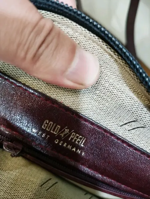 这款德国金箭斜挎包质感超出预期唯一美中不足的就是那个内衬有粉末出来时间长了吧。，酒红色真皮细腻有光泽，做工扎实走线工整。内里容量充足，分层收纳很实用，复古款式百搭耐看，背带舒适日常出门超合适，购物体验还行吧。