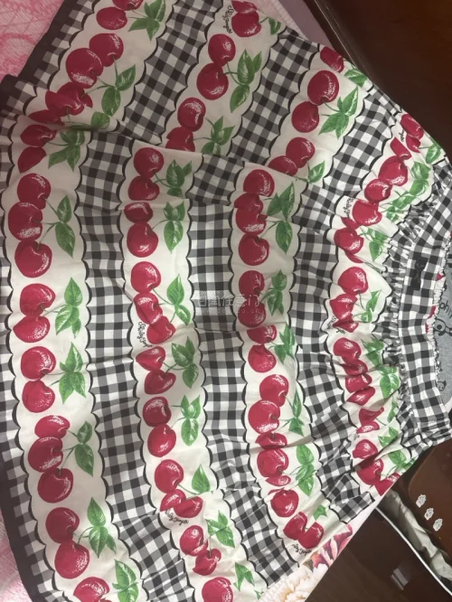 这条半身裙采用松紧腰设计，穿脱方便。黑白格纹搭配饱满鲜红的樱桃印花，层层拼接的蛋糕版型，甜美复古，面料轻薄，充满少女田园感。黑白格子底色和樱桃图案交错排列，波浪花边分割色块，裙摆宽松蓬松，整体元气满满，很适合日常休闲穿搭。