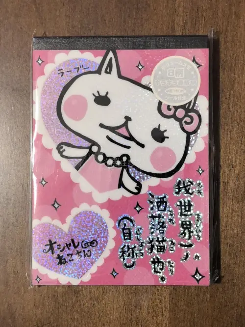 挖煤姬体验大成功！
收到这款日系卡通风格的闪面便签本，大爱！整体以粉色为基底，印着戴蝴蝶结、配珍珠颈饰的拟人化可爱猫咪形象，搭配镭射闪粉爱心与星星装饰，印有日文趣味标语，还附带贴纸配件，是充满复古Y2K童趣感的文具。