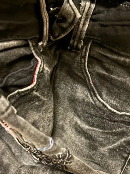 这条黑灰做旧水洗牛仔，满布袋口刺绣，银闪十字架、紫调字母、骷髅、粉五角星元素堆在一起，亚古着感直接拉满，细节巨多，每一处绣花都很扎实，不是那种廉价浮线，复古又带点朋克甜酷味儿，上身很有辨识度，不容易撞款。