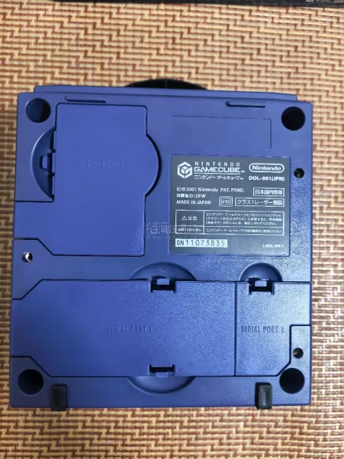 这是一台任天堂GameCube（NGC）家用游戏机，经典的紫罗兰紫配色。
机身上方是光盘仓，正面配备四个手柄接口，下方有SLOT‑A、SLOT‑B两个记忆卡插槽，右下角印有ATI的标识，代表该机的图形芯片由ATI提供。
 这台是任天堂2001年推出的第六代家用主机，...