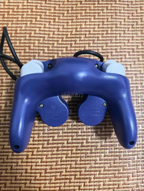 这是一台任天堂GameCube（NGC）家用游戏机，经典的紫罗兰紫配色。
机身上方是光盘仓，正面配备四个手柄接口，下方有SLOT‑A、SLOT‑B两个记忆卡插槽，右下角印有ATI的标识，代表该机的图形芯片由ATI提供。
 这台是任天堂2001年推出的第六代家用主机，...