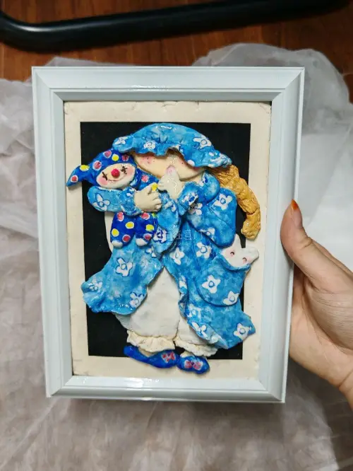 海外淘来的手作小物件，肌理感十足，抱着小丑玩偶的睡衣女孩、衣兜悄悄探头的小兔子，每一处细节都充满巧思。蓝底碎花柔和耐看，自带复古温柔的氛围，白框衬得画面格外精致。
跨越时差和距离收来独一份的藏品，这种淘老好物的快乐真的很难得，摆在桌面氛围感拉满，太喜欢这份跨越山海的...