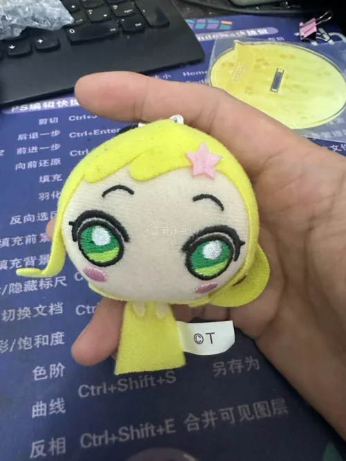小魔女Doremi妖精挂件。采用毛绒布料和刺绣工艺制成，整体为黄色，复刻了角色标志性的金色双马尾、绿色大眼睛和头顶的粉色星星发夹