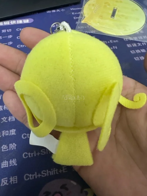 小魔女Doremi妖精挂件。采用毛绒布料和刺绣工艺制成，整体为黄色，复刻了角色标志性的金色双马尾、绿色大眼睛和头顶的粉色星星发夹