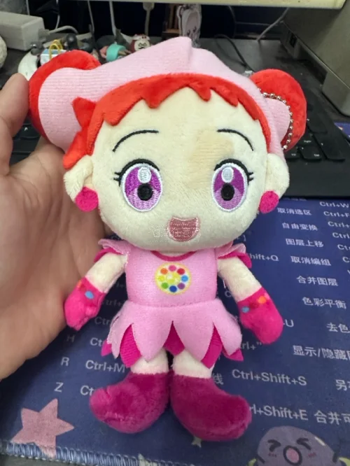 小魔女Doremi玩偶。日本动画《小魔女Doremi》主角春风Doremi为原型的毛绒玩偶，还原了Doremi标志性的红色短发和粉色服装，胸前的转换器是魔女见习生的象征